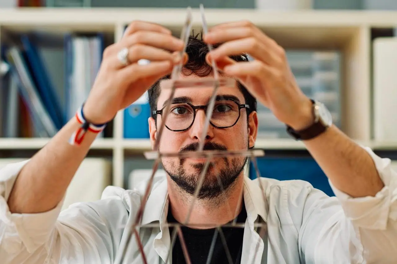 Simon Marcialis construit un château de cartes, geste précis et concentré